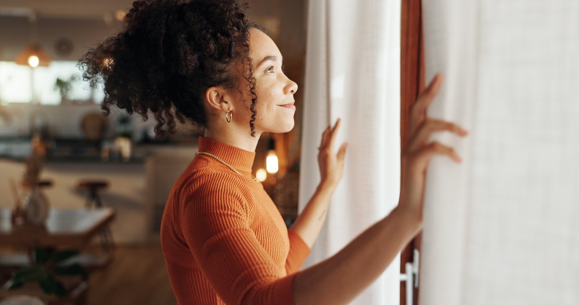 A woman opens her curtains to morning light